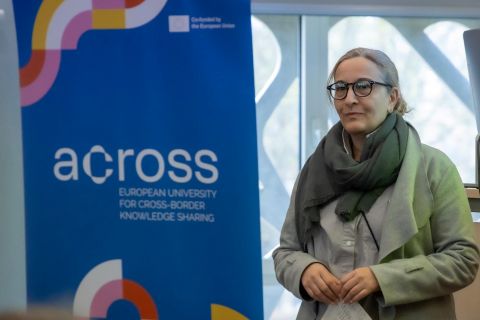 Uczestnik wykładów w ramach Dni Rumuńskich na Politechnice Białostockiej przed plakatem Across