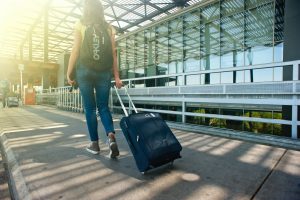 Girl with backpack and suitcase is at the airport.