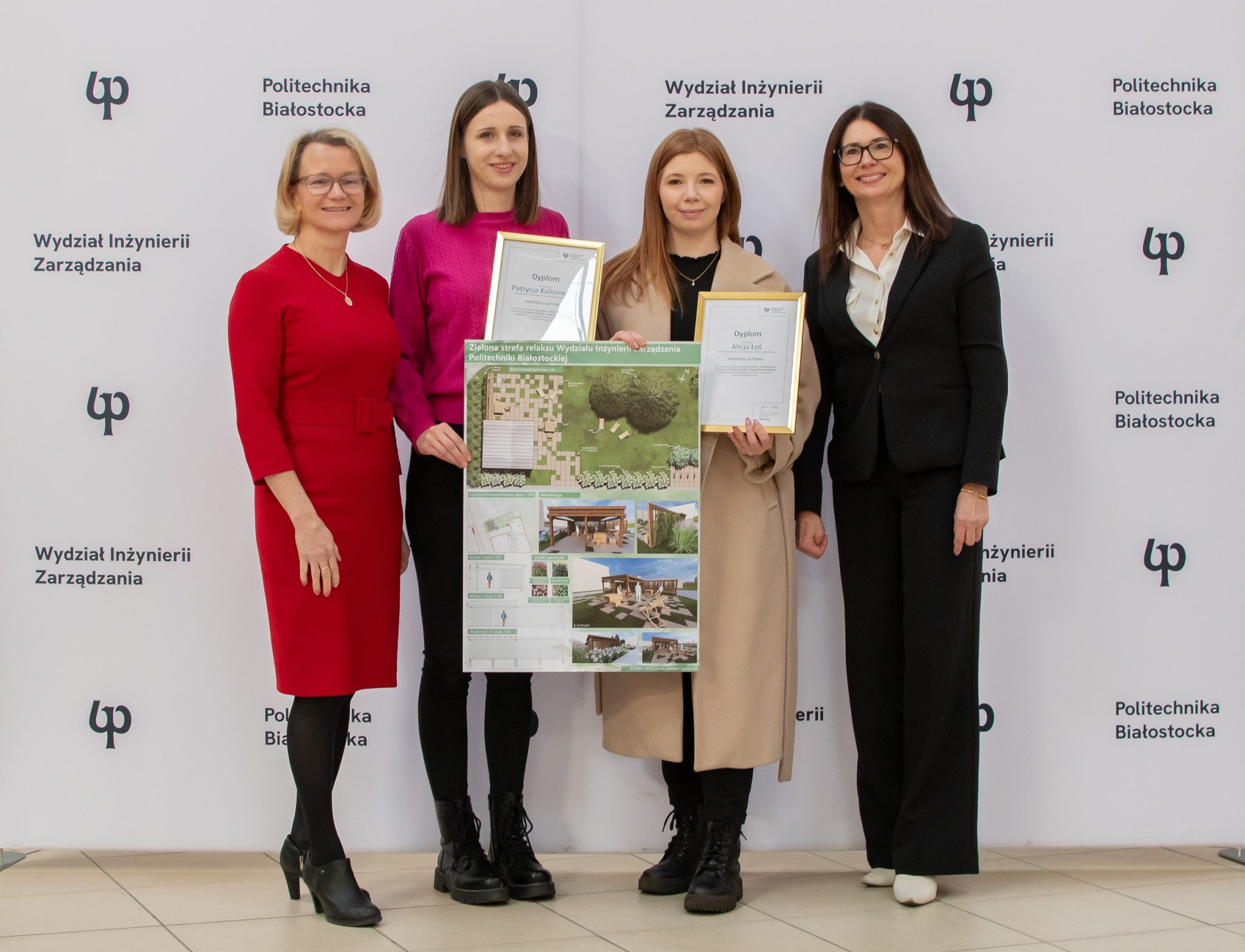 Cztery eleganckie osoby, kobiety. Dwie z kobiet prezentują dyplomy oraz nagrodzony projekt. W tle ścianka foto z napisami Wydział Inżynierii Zarządzania oraz logiem PB