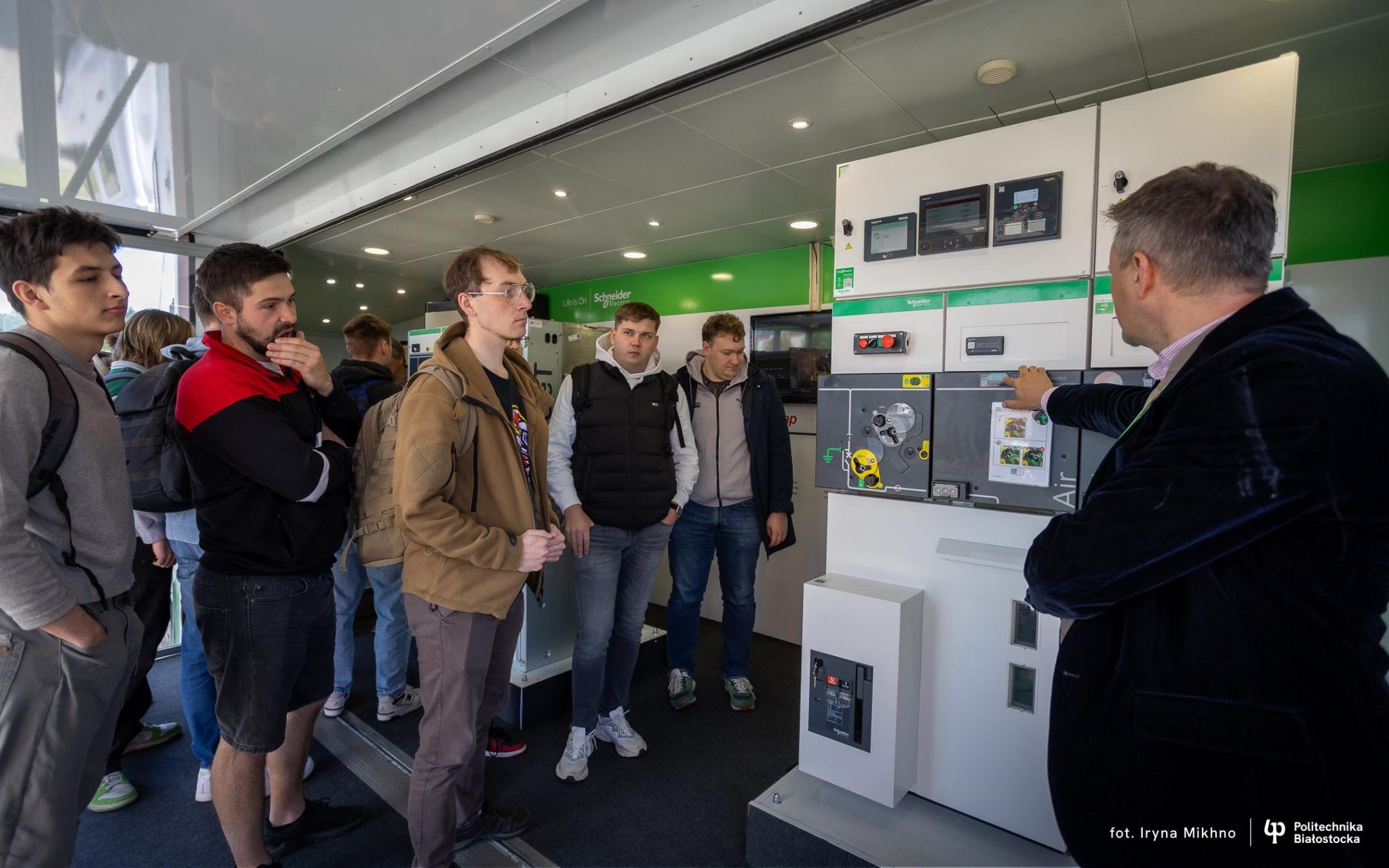 Grupa studentów przygląda się rozdzielnicom elektrycznym średniego napięcia