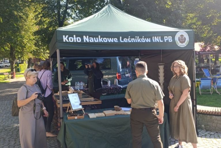 Zielony namiot wystawienniczy Koła Naukowego Leśników Politechniki Białostockiej, pod którym przedstawiciele koła prezentują materiały edukacyjne i okazowe zwiedzającym.