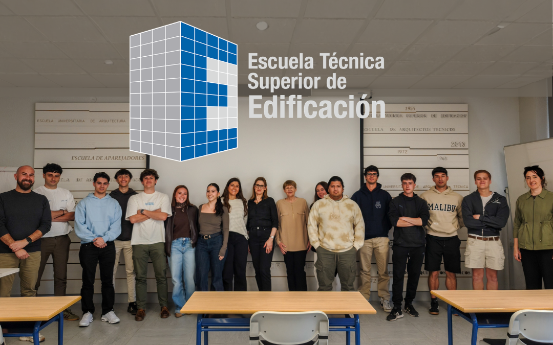 Kilkunastoosobowa grupa studentów stojąca w sali wykładowej, przed ścianą z logo i napisem „Escuela Técnica Superior de Edificación”.