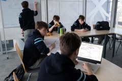 A-group-of-young-boys-sitting-at-a-table-with-a-laptop