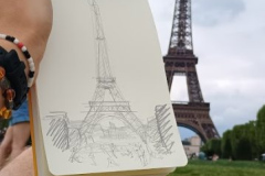 A-man-holding-a-pen-and-drawing-a-picture-of-the-eiffel-tower