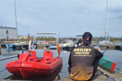 A-man-sitting-on-a-dock-next-to-a-small-boat