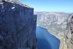 A-man-standing-on-a-cliff-overlooking-a-lake