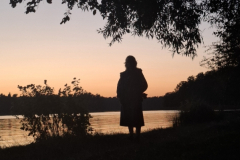 A-person-standing-by-a-lake-at-sunset