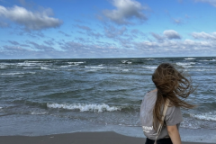 A-woman-walking-on-the-beach-with-her-hair-blowing-in-the-wind