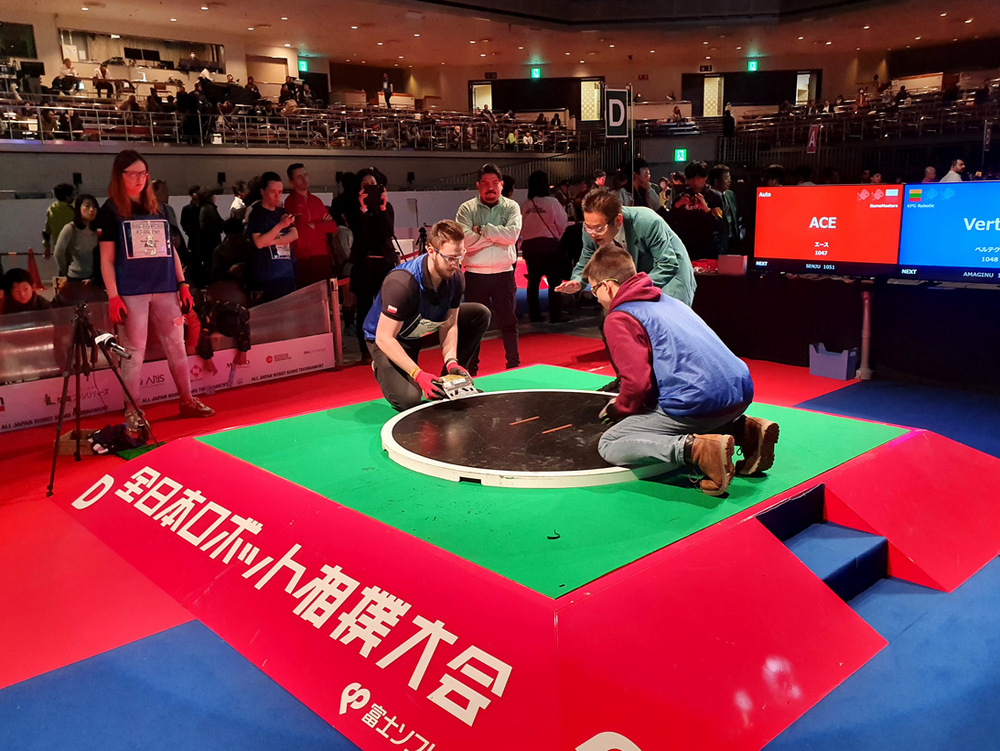 SumoMasters wystartowali na zawodach All Japan Robot-Sumo Tournament 2019 w Tokio. Zdjęcie przedstawia ring i studentów operujących robotami