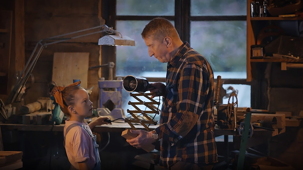 kadr z filmu promocyjnego Politechniki Białostockiej: dziadek pokazuje dziewczynce jak włącza się starą lampę