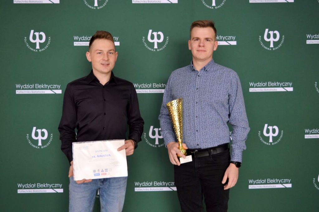 Dwóch studentów trzyma dyplom i puchar