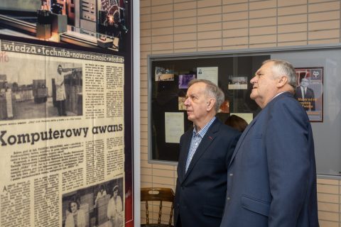 Mężczyźni oglądają powiększenie starej gazety na wystawie