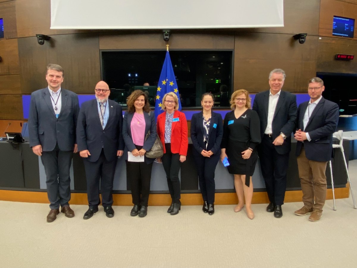 Osiem osób pozuje na tle flagi Unii Europejskiej