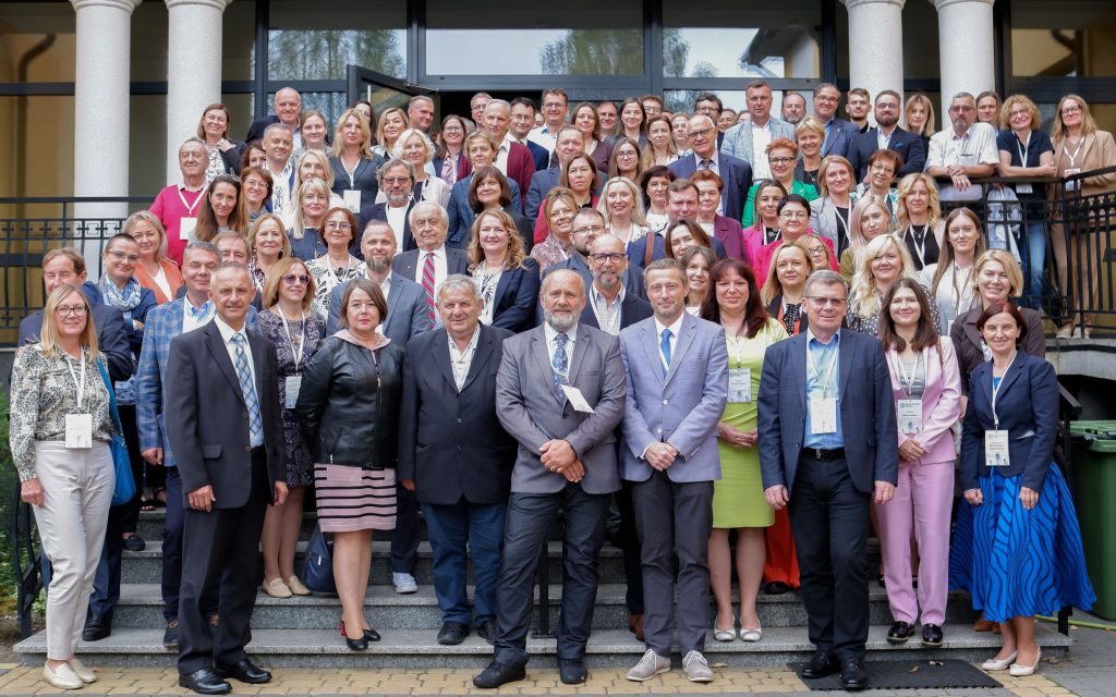 A large group of people pose for a photo on the entrance steps of the building
