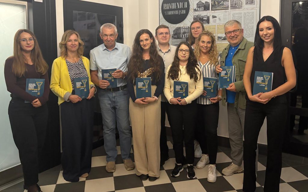 Grupa mężczyzn i kobiet pozuje z książkami w rękach. zdjęcie zbiorowe autorów monografii naukowej