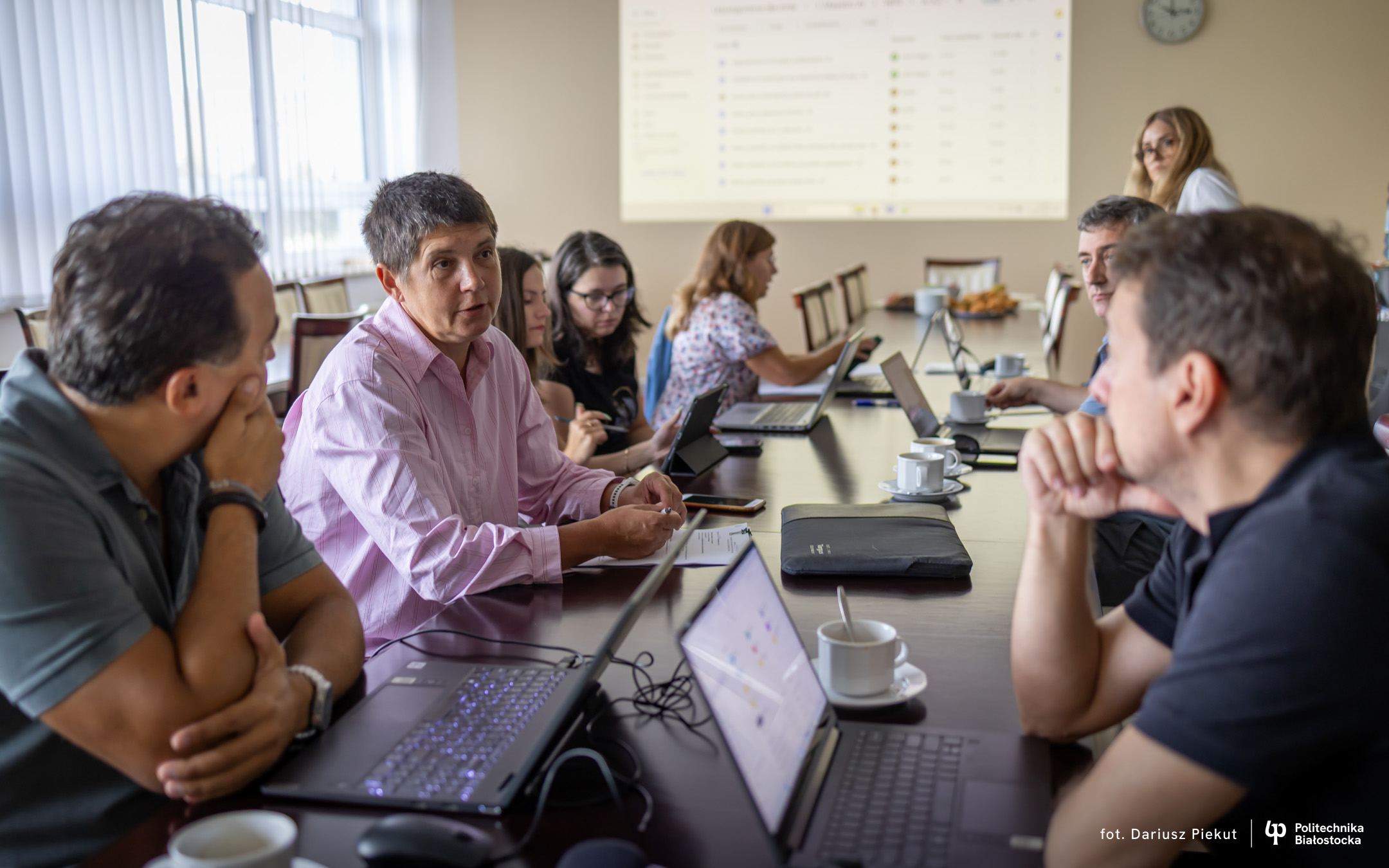 grupa osób siedząca przy stole pogrążona w dyskusji