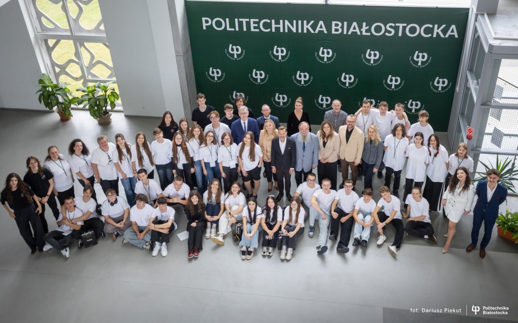 Group photo of students and staff in front of a banner with the inscription Politechnika Białostocka in the university hall