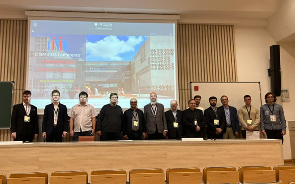 grupa uczestników na tle ekranu z prezentacją konferencji CISIM