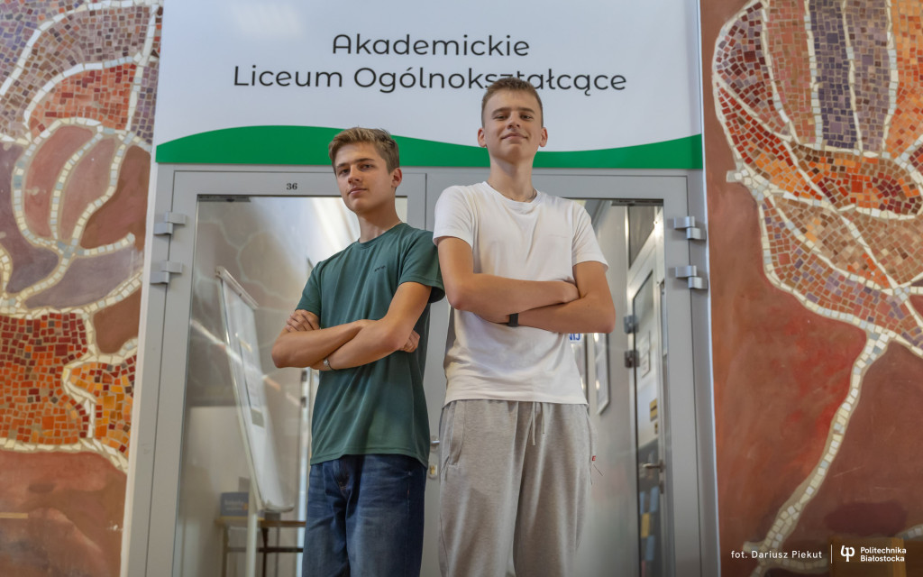 Dwóch chłopców - uczniowie ALO PB, stojący przed wejściem do szkoły
