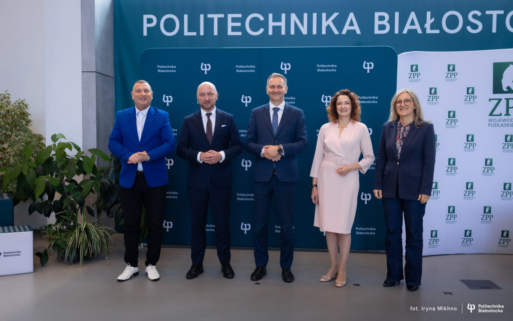 5 osób stojących przy ściance z logo PB - uczestnicy konferencji prasowej zapowiadającej Kongres Smart Village Polska na Politechnice Białostockiej