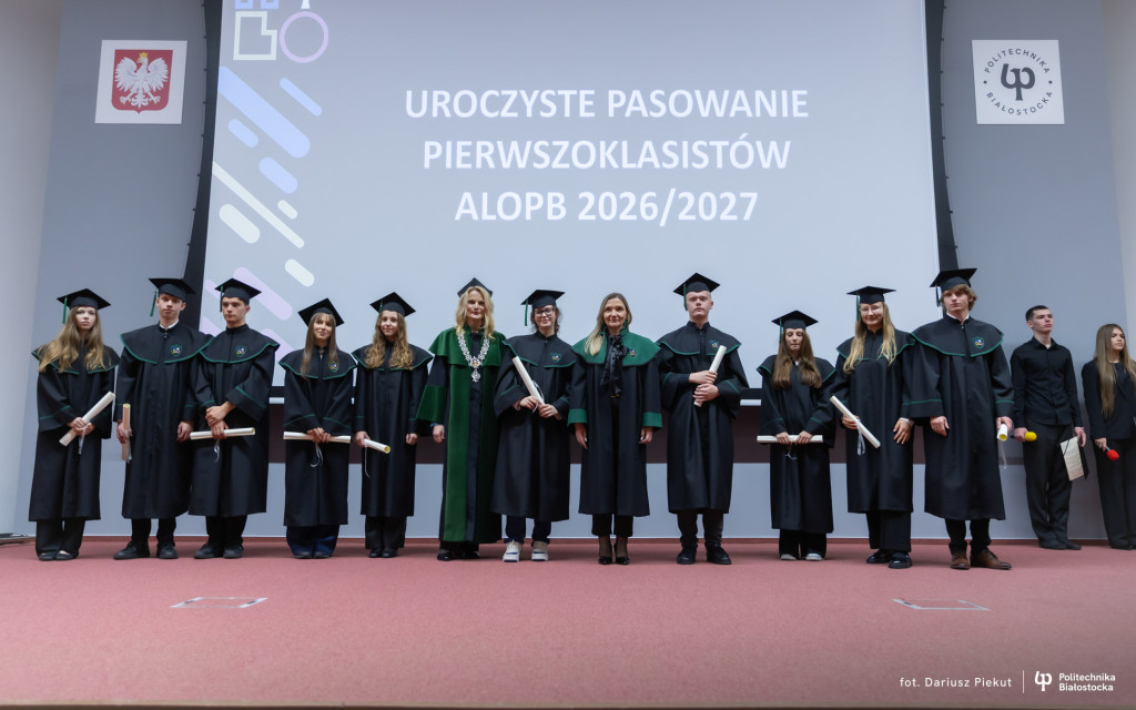 uczniowie w togach na scenie, trzymają akty ślubowania ALO PB